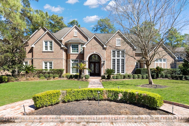 view of front of property featuring french doors, a front lawn, and brick siding