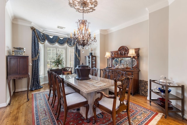 dining room with light wood-style flooring, visible vents, and ornamental molding