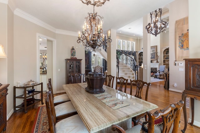 dining area featuring a warm lit fireplace, dark wood-style flooring, a chandelier, and crown molding