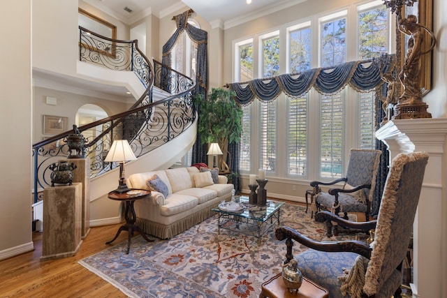 living area featuring a high ceiling, wood finished floors, baseboards, ornamental molding, and stairway