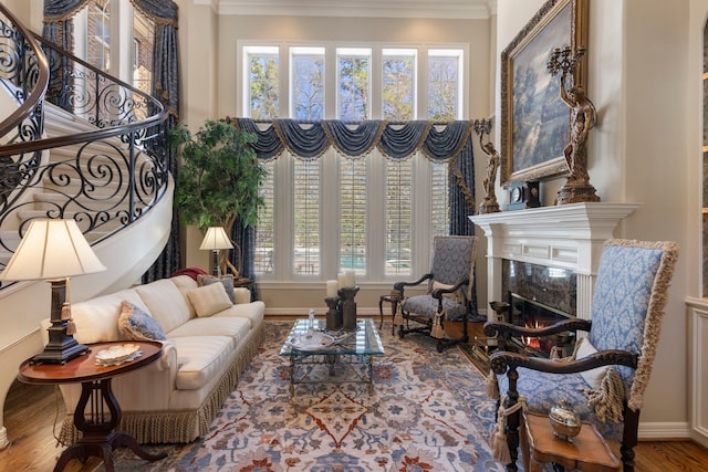 living room with ornamental molding, wood finished floors, a healthy amount of sunlight, and a premium fireplace