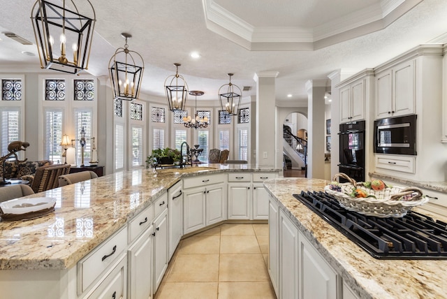 kitchen with black appliances, light stone counters, light tile patterned flooring, and decorative light fixtures