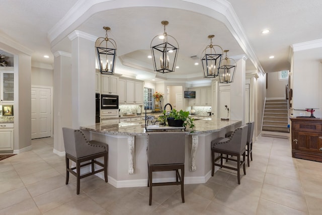 kitchen with stone countertops, built in microwave, hanging light fixtures, and a kitchen breakfast bar