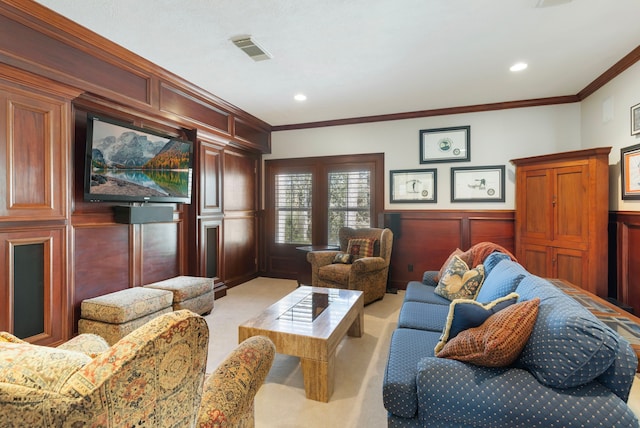 living room with wainscoting, visible vents, crown molding, and light colored carpet