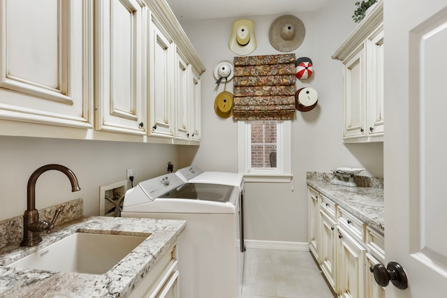 washroom with light tile patterned floors, separate washer and dryer, a sink, baseboards, and cabinet space