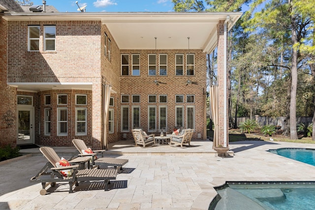 rear view of property with a fenced in pool, brick siding, an outdoor fire pit, a patio area, and fence