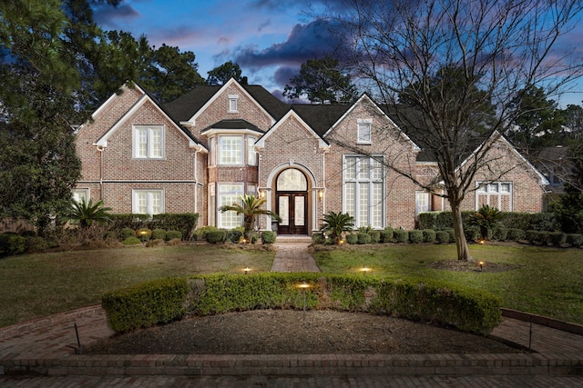 view of front facade with a yard, french doors, and brick siding