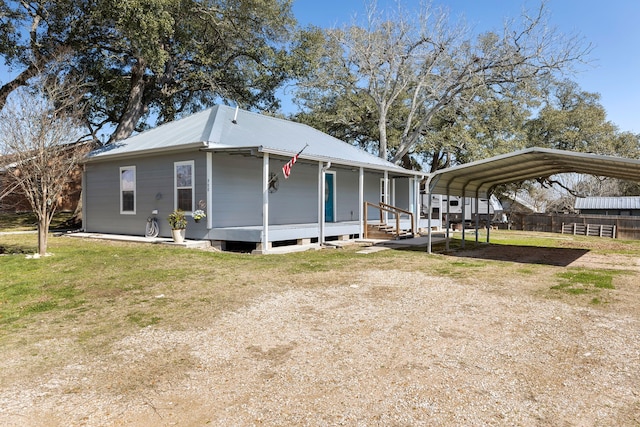 view of front of house featuring dirt driveway, fence, a front lawn, a porch, and a carport