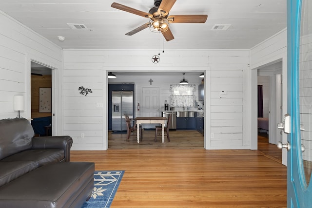 living room featuring wood finished floors, visible vents, and a ceiling fan