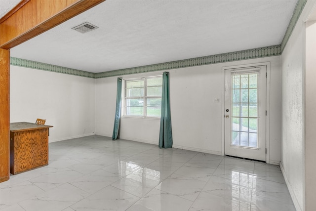 spare room featuring marble finish floor, baseboards, visible vents, and a textured ceiling