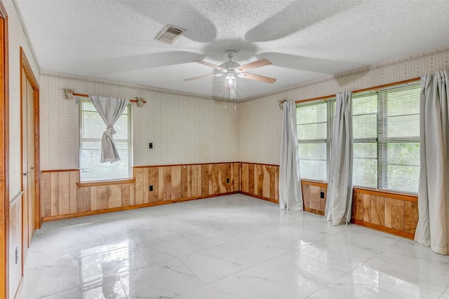 spare room featuring wallpapered walls, visible vents, a ceiling fan, marble finish floor, and a textured ceiling