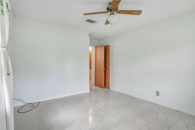 empty room with marble finish floor, visible vents, ceiling fan, and baseboards