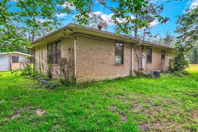 view of home's exterior with a yard, central AC unit, and brick siding