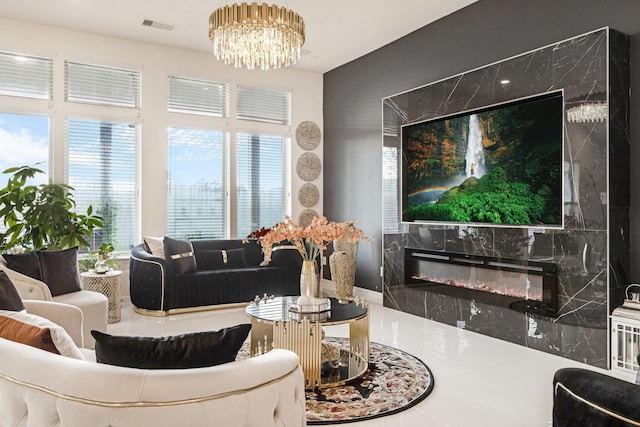 living area featuring a glass covered fireplace, visible vents, and a notable chandelier