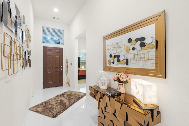 foyer with baseboards, a high ceiling, visible vents, and tile patterned floors