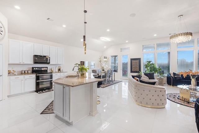 kitchen with hanging light fixtures, range with two ovens, stainless steel microwave, and white cabinetry