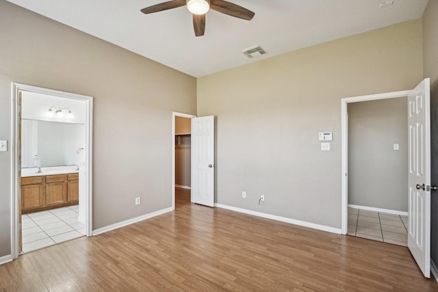 unfurnished bedroom featuring baseboards, visible vents, ensuite bath, and light wood finished floors