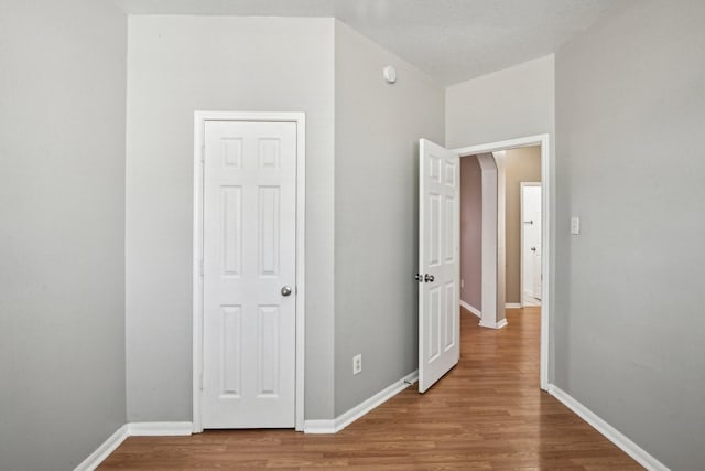 corridor with baseboards and wood finished floors