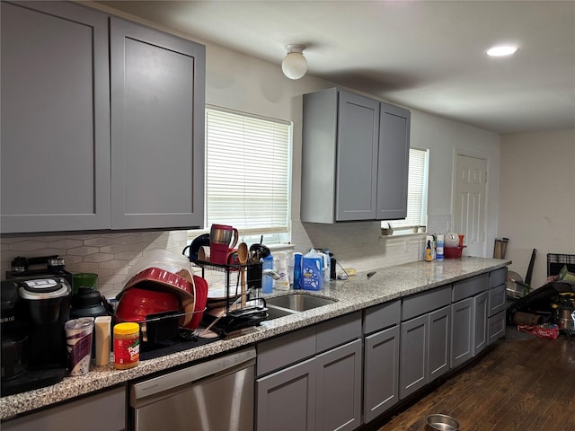 kitchen featuring backsplash, stainless steel dishwasher, gray cabinetry, and dark wood-style floors