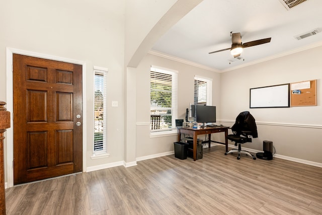 entrance foyer featuring arched walkways, baseboards, crown molding, and light wood finished floors