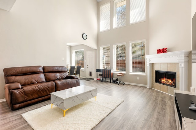 living area featuring baseboards, a tiled fireplace, and light wood finished floors