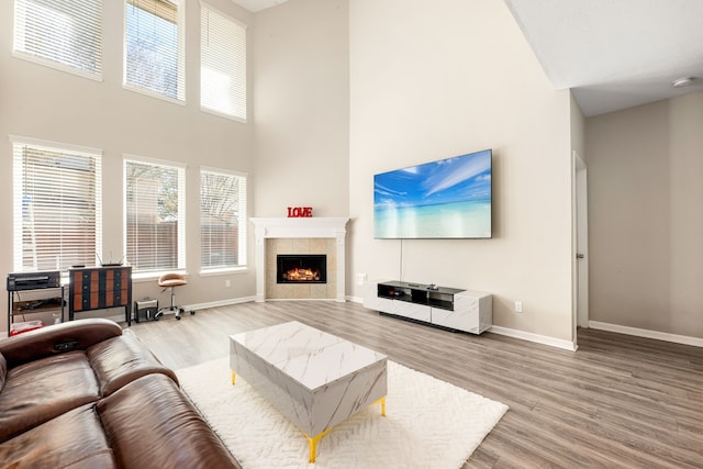 living area with light wood finished floors, baseboards, a fireplace, and a high ceiling