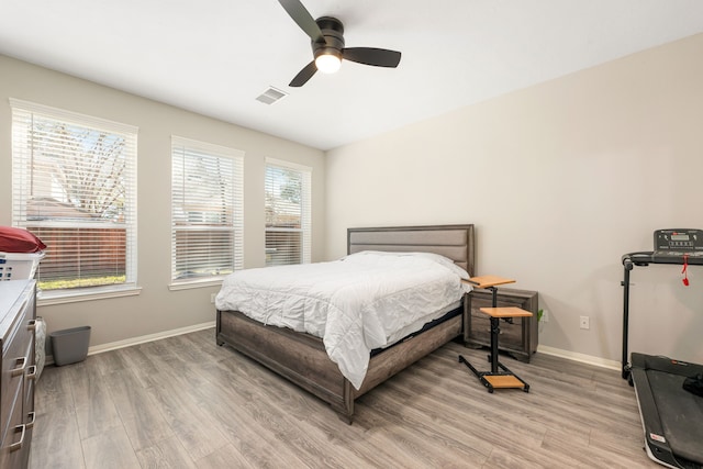 bedroom with light wood finished floors, visible vents, and baseboards