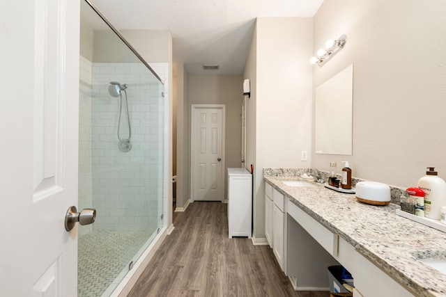 full bathroom with wood finished floors, visible vents, vanity, baseboards, and a stall shower