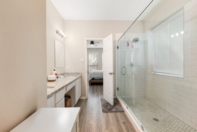 bathroom with double vanity, ensuite bathroom, a sink, a shower stall, and wood finished floors