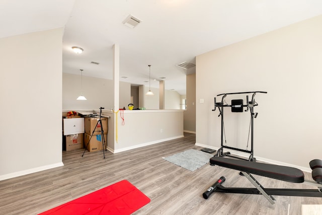 exercise room with baseboards, visible vents, and wood finished floors