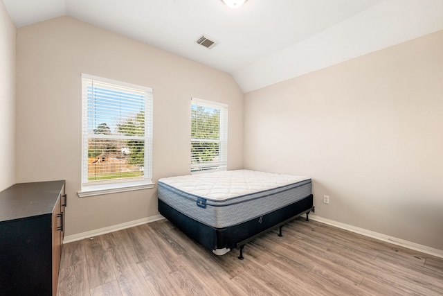 bedroom featuring visible vents, vaulted ceiling, baseboards, and wood finished floors