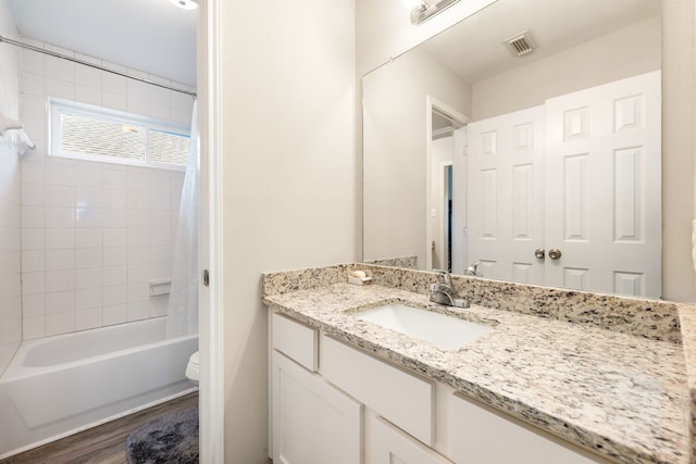 full bathroom with toilet, wood finished floors, vanity, visible vents, and shower / bath combo with shower curtain