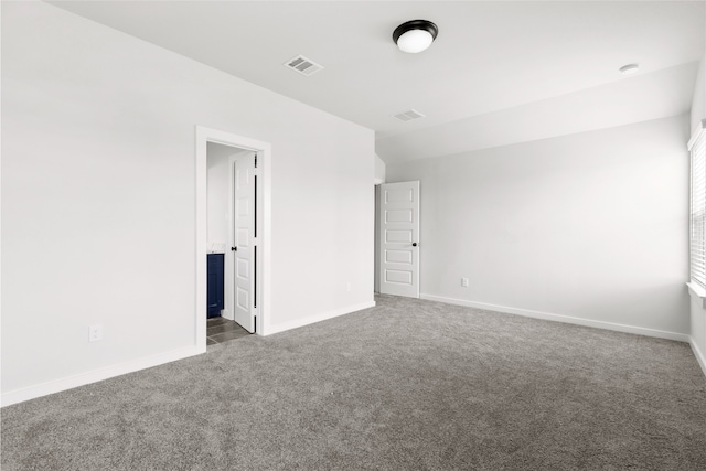 spare room with baseboards, visible vents, and dark colored carpet