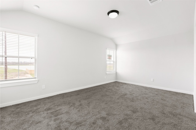 unfurnished room with vaulted ceiling, dark colored carpet, and baseboards