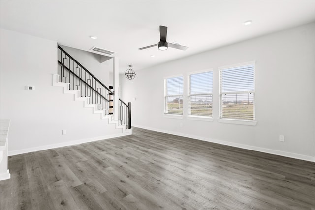 unfurnished living room featuring visible vents, dark wood-type flooring, a ceiling fan, baseboards, and stairs