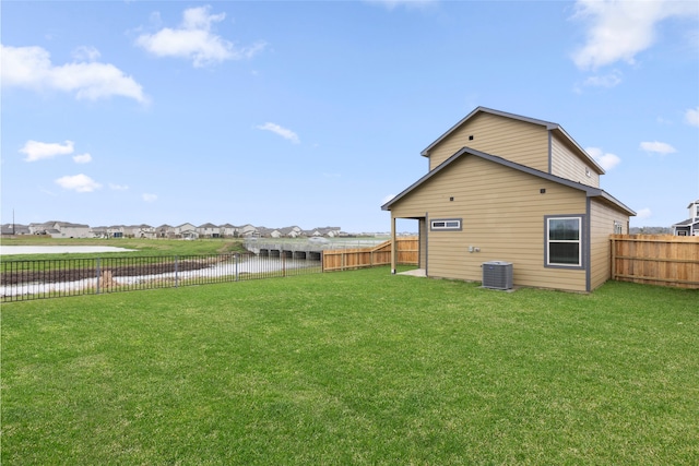 rear view of house with a lawn, a water view, and a fenced backyard