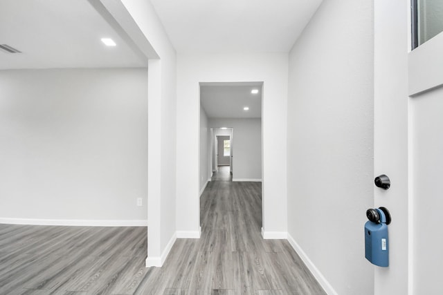 hall featuring light wood-style floors, visible vents, and baseboards