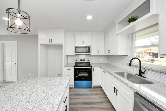 kitchen featuring light stone counters, hanging light fixtures, appliances with stainless steel finishes, white cabinets, and a sink