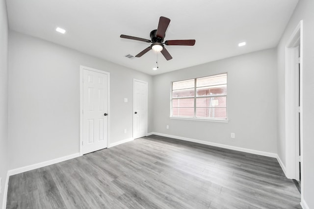 unfurnished bedroom featuring recessed lighting, wood finished floors, a ceiling fan, visible vents, and baseboards