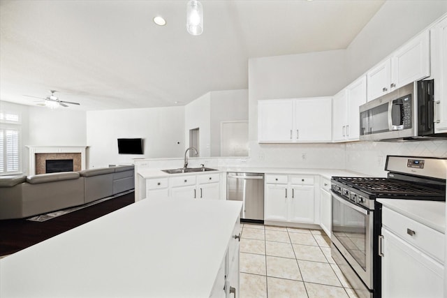 kitchen with a sink, white cabinets, open floor plan, light countertops, and appliances with stainless steel finishes