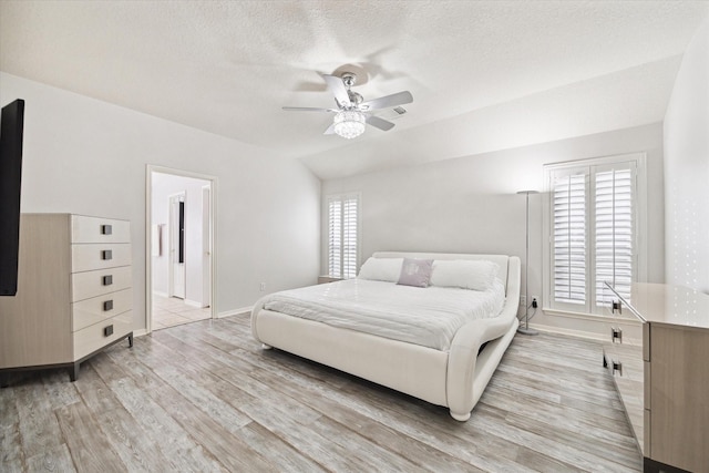 bedroom with baseboards, lofted ceiling, ceiling fan, a textured ceiling, and light wood-style floors