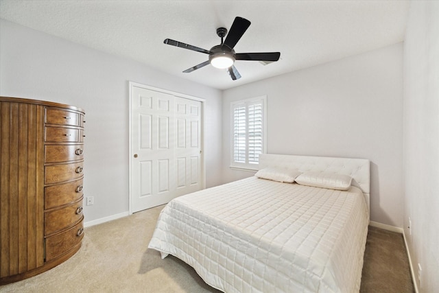 bedroom featuring a ceiling fan, baseboards, a closet, and light colored carpet