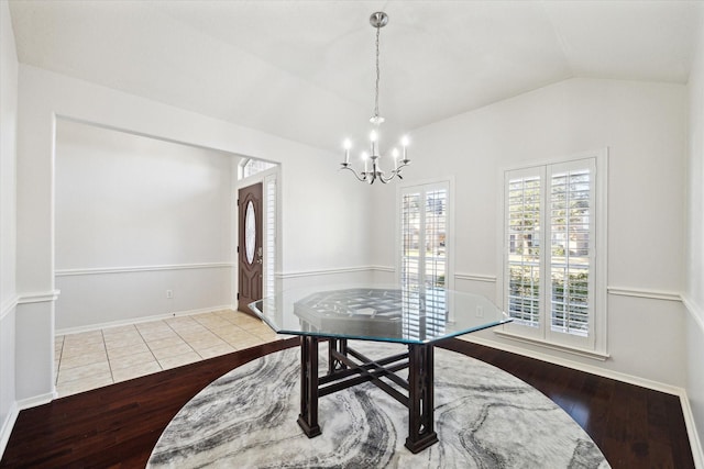 dining space with vaulted ceiling, light wood-type flooring, baseboards, and a notable chandelier