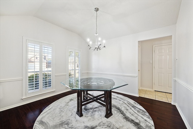 dining space featuring a chandelier, lofted ceiling, baseboards, and wood finished floors