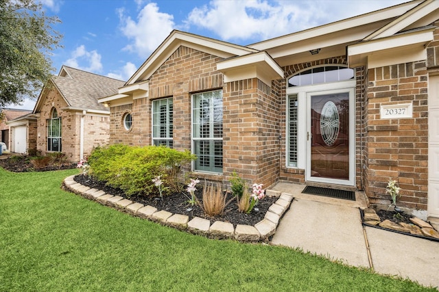 entrance to property with a lawn and brick siding