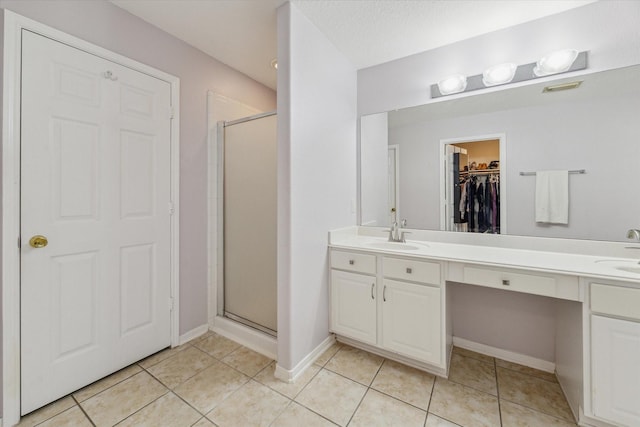 bathroom with tile patterned flooring, a sink, visible vents, a spacious closet, and a stall shower