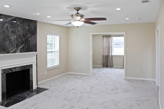 unfurnished living room featuring a premium fireplace, carpet flooring, a wealth of natural light, and recessed lighting