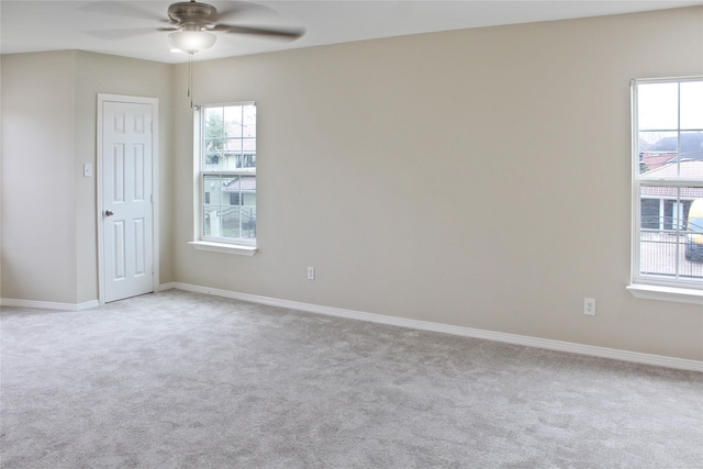 carpeted empty room featuring ceiling fan and baseboards