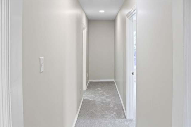 hallway featuring carpet and baseboards