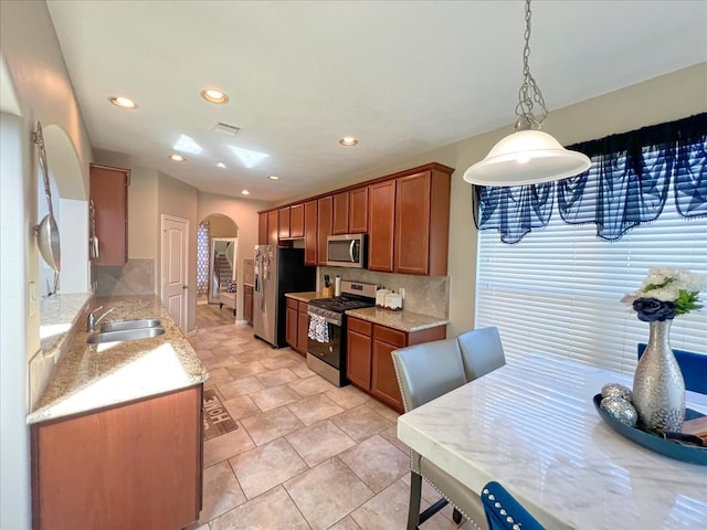 kitchen with arched walkways, stainless steel appliances, tasteful backsplash, visible vents, and a sink